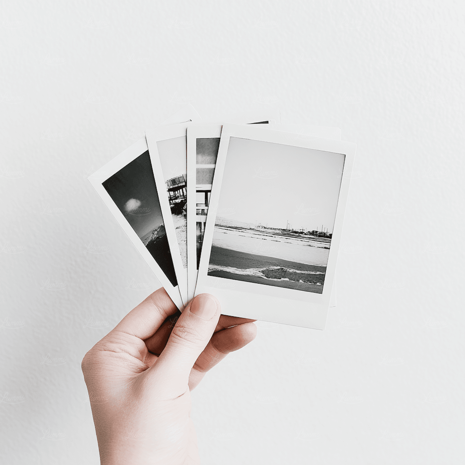 A hand holding a stack of printed travel photographs